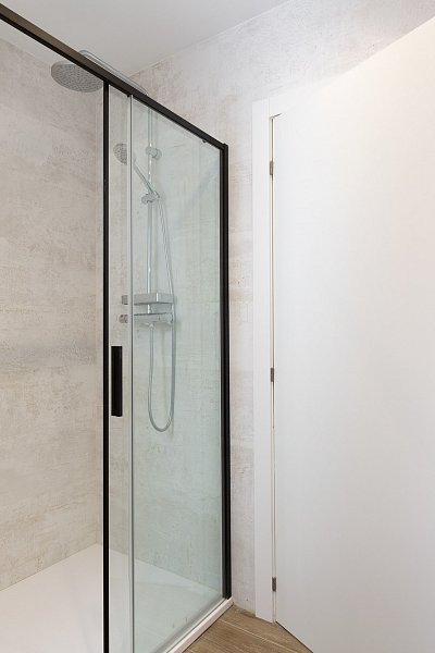 Spacious walk-in shower with a black metal frame in a stylish holiday apartment in Barcelona.